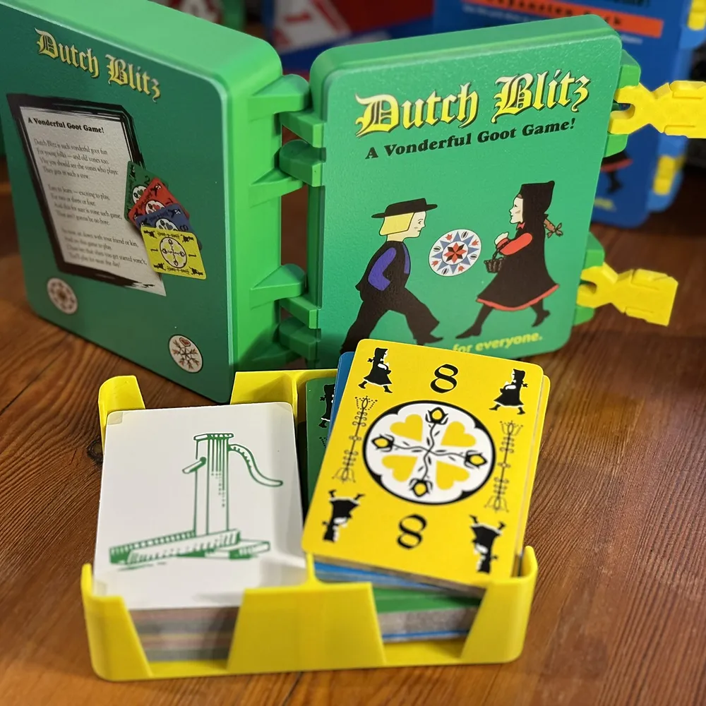 a green case opened out, rules inside the lid and cards in a yellow tray