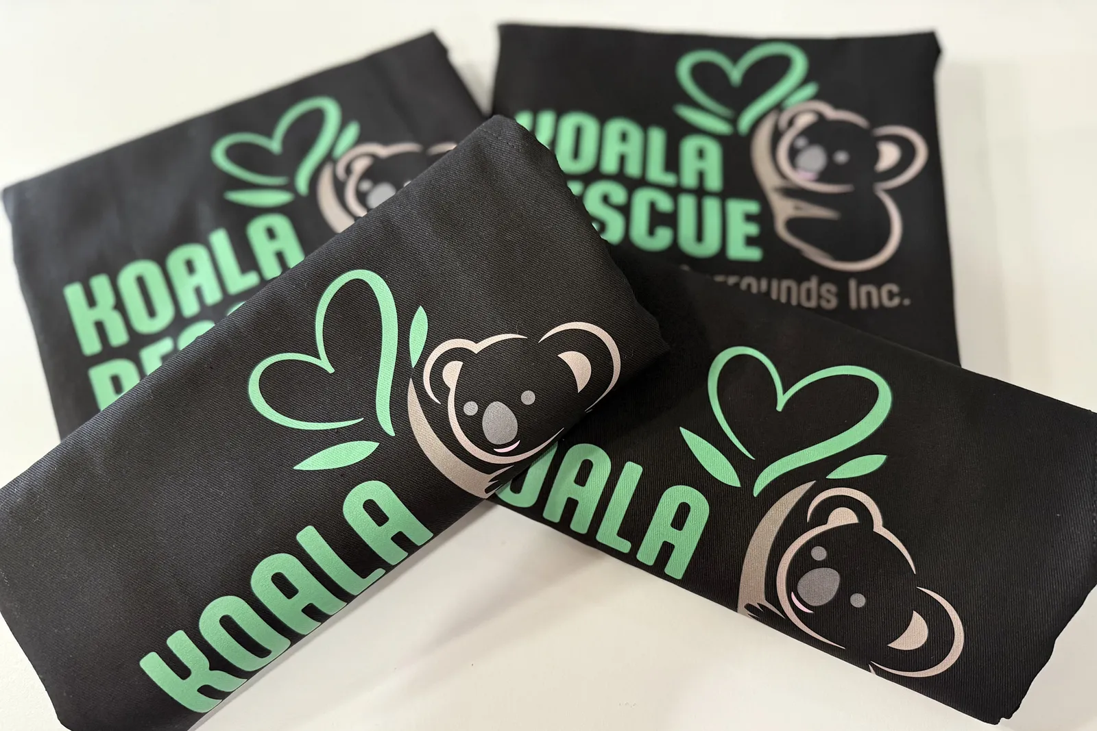 black tees printed with a koala charity logo
