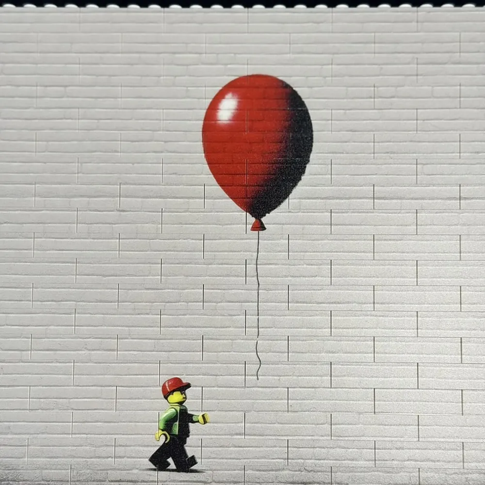 a white brick wall printed with a red balloon, with a minifigure walking past